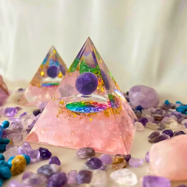 Conjunto de pirâmides de Orgonite com Quartzo Rosa, rodeadas por outras pedras e cristais, destacando a harmonia dos 7 Chakras.